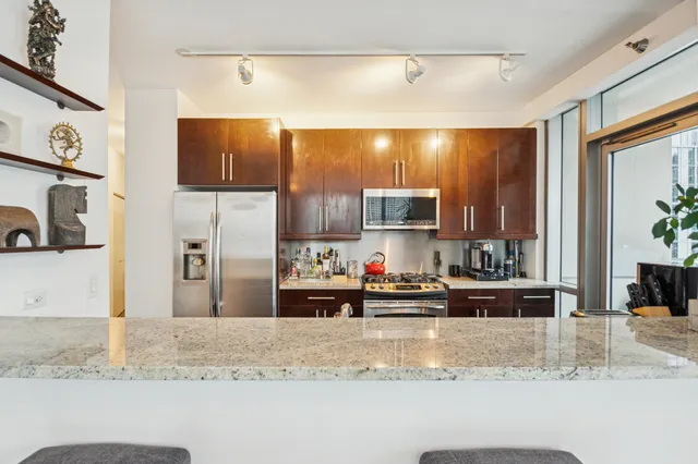 a kitchen with stainless steel appliances kitchen island granite countertop a sink and a refrigerator