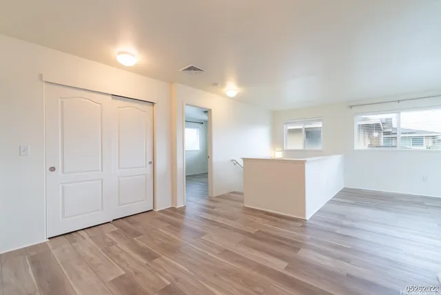 a view of a kitchen and an empty room with wooden floor and a kitchen