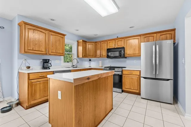 a kitchen with stainless steel appliances kitchen island granite countertop a sink dishwasher a oven a dining table and chairs with wooden floor