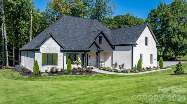a front view of a house with a yard outdoor seating and mountain view in back