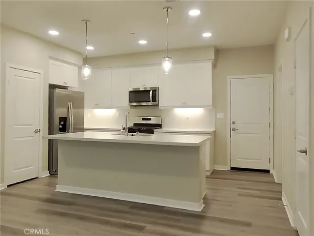 a view of kitchen with stainless steel appliances wooden floor and refrigerator