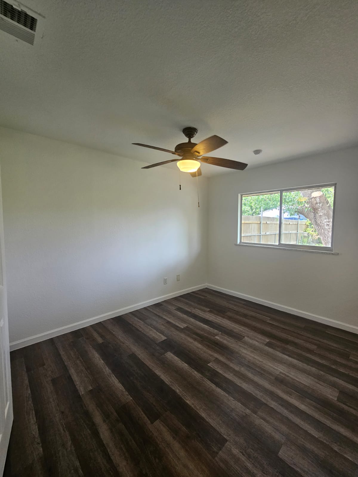 1401 Trinity Street Lockhart, TX 78644 - Photo 10 of 31 Room featuring wood-finish flooring, a ceiling fan with integrated lighting, and a single window