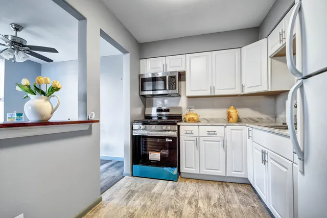 a kitchen with stainless steel appliances granite countertop a refrigerator sink and white cabinets