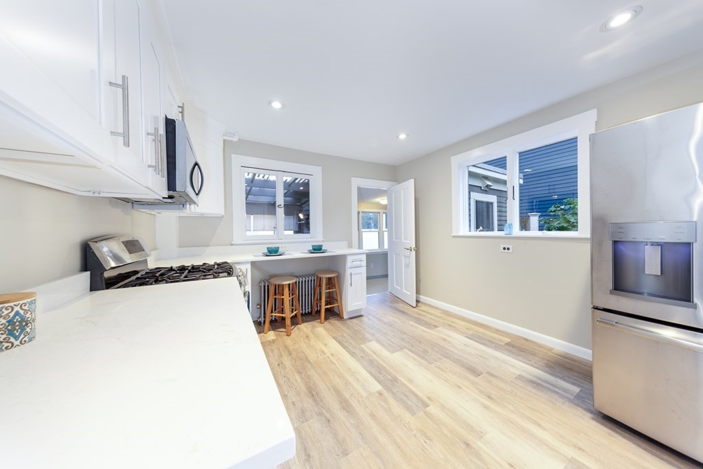 7 Herbert Street Salem, MA 01970 - Photo 3 of 17 a kitchen with stainless steel appliances granite countertop a stove a sink a refrigerator and white cabinets with wooden floor