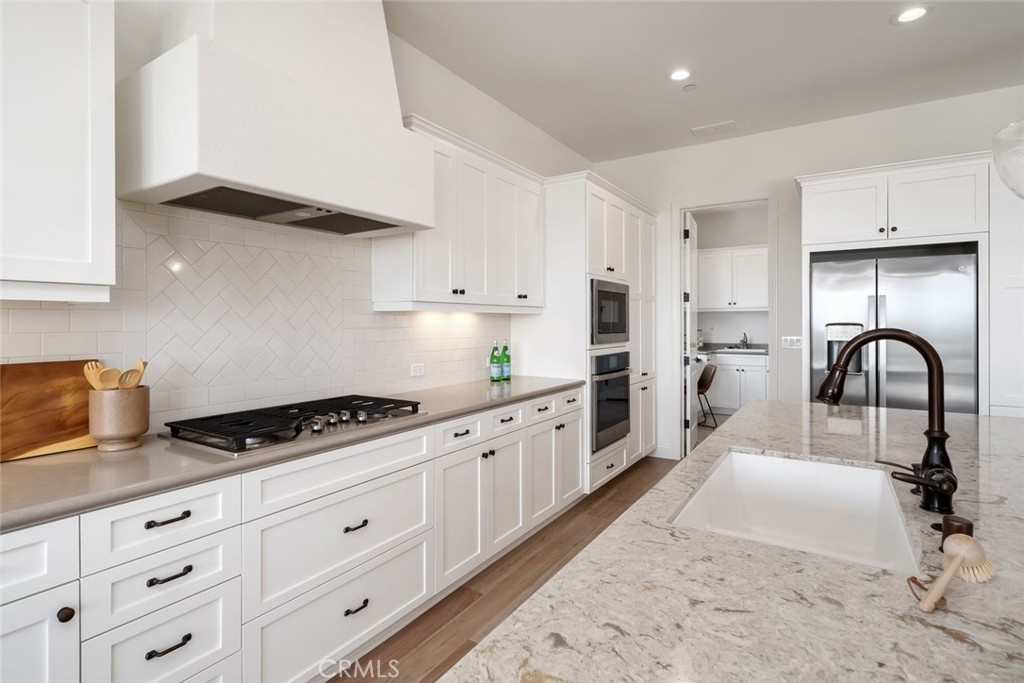 1622 Eucalyptus Road Nipomo, CA 93444 - Photo 7 of 73 a kitchen with granite countertop a stove a sink dishwasher and white cabinets with wooden floor