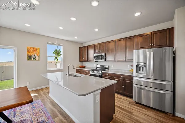 a kitchen with a refrigerator a stove a sink dishwasher and wooden cabinets with wooden floor