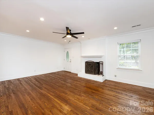 an empty room with wooden floor fireplace and windows