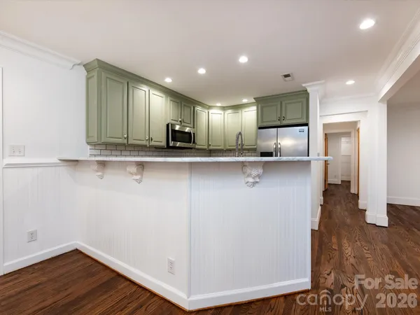 an empty room with wooden floor cabinet and windows
