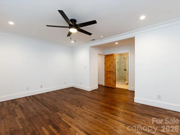 an empty room with wooden floor and a ceiling fan