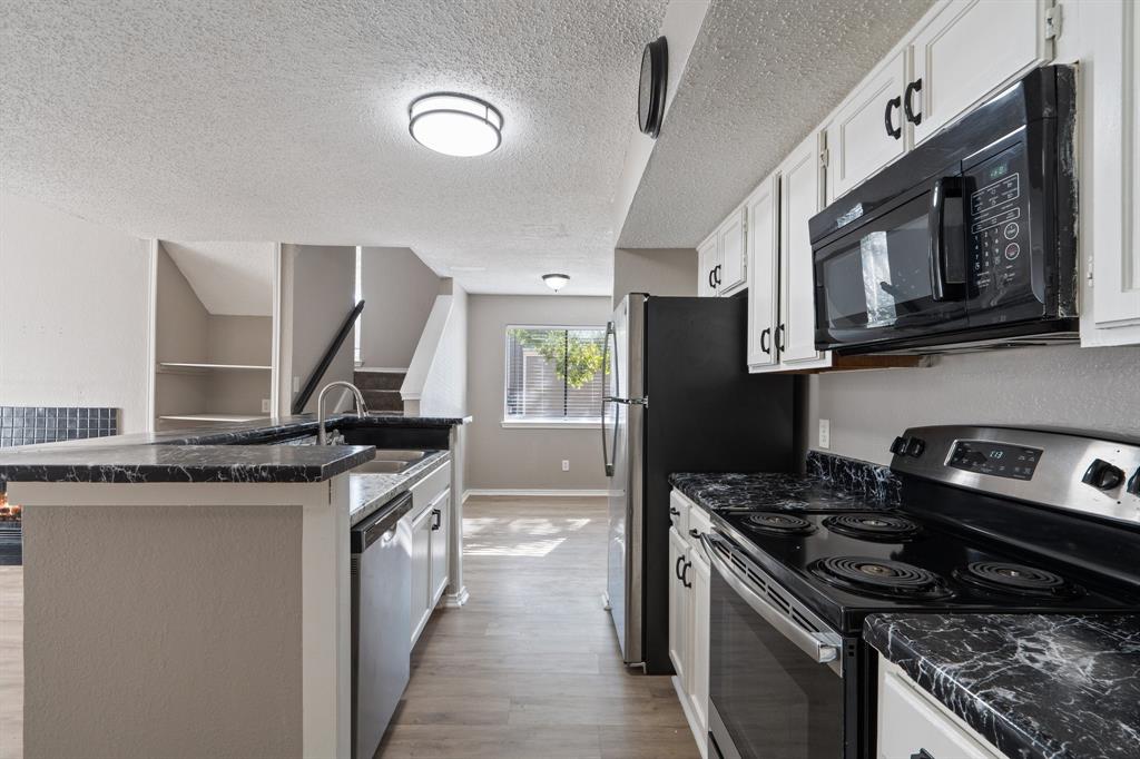 9831 Walnut Street, Unit 205 Dallas, TX 75243 - Photo 13 of 29 Kitchen with white cabinets, sink, light wood-type flooring, a textured ceiling, and stainless steel appliances