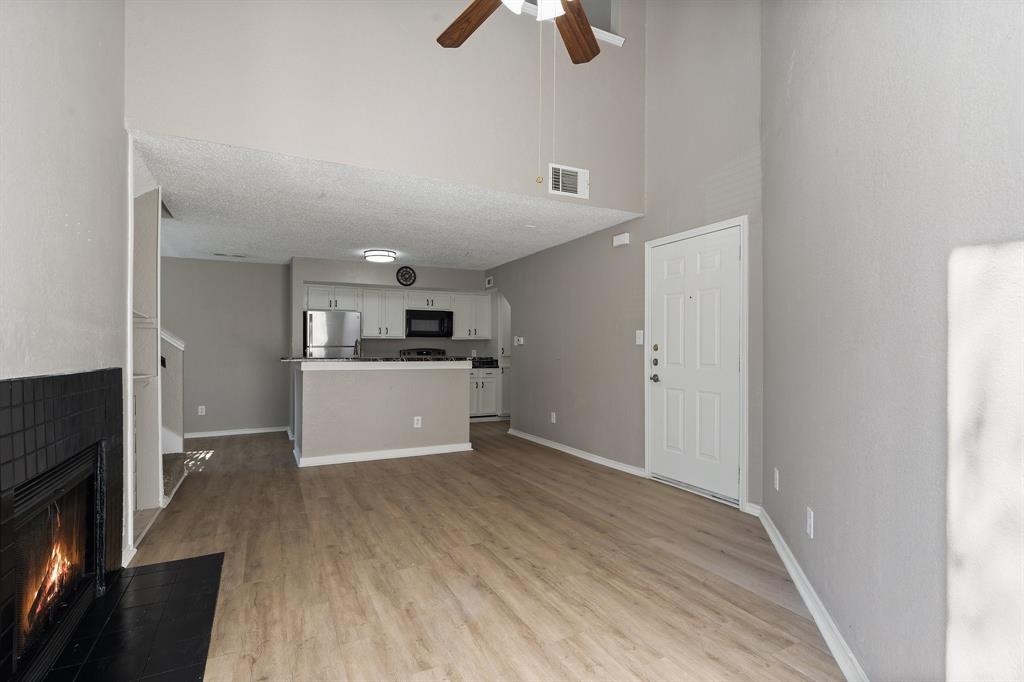 9831 Walnut Street, Unit 205 Dallas, TX 75243 - Photo 6 of 29 Unfurnished living room featuring a towering ceiling, a textured ceiling, light hardwood / wood-style floors, and ceiling fan