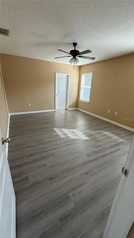 en empty room with wooden floor ceiling fan and window