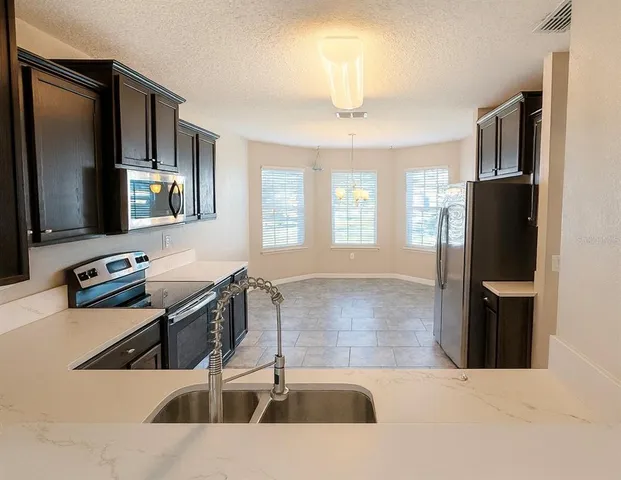 a kitchen with stainless steel appliances kitchen island granite countertop a refrigerator and a stove top oven