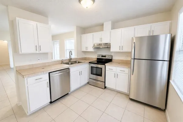 a kitchen with white cabinets white appliances and sink