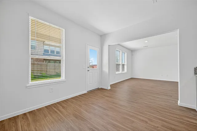 a view of an empty room with wooden floor and a window