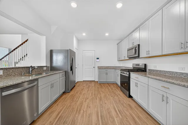 a kitchen with granite countertop a sink cabinets stainless steel appliances and a counter space