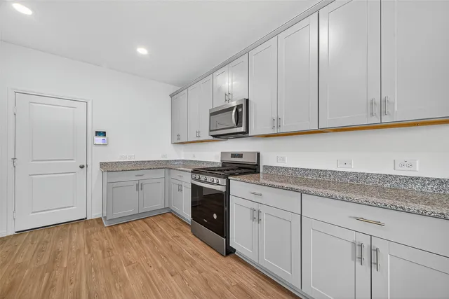 a kitchen with stainless steel appliances granite countertop a stove a sink and a white cabinets