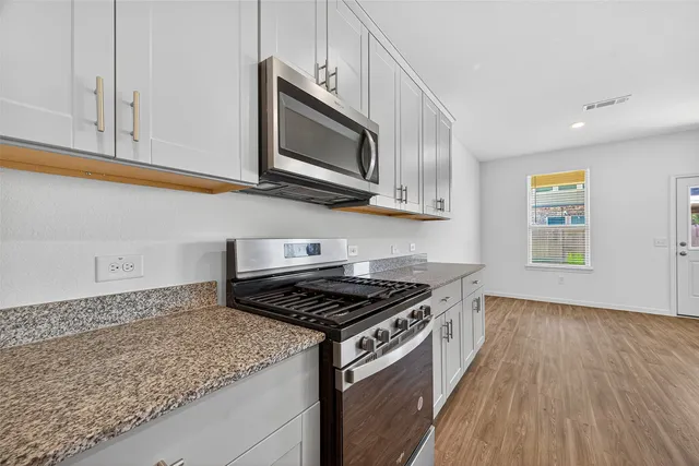 a kitchen with stainless steel appliances granite countertop a stove and a microwave
