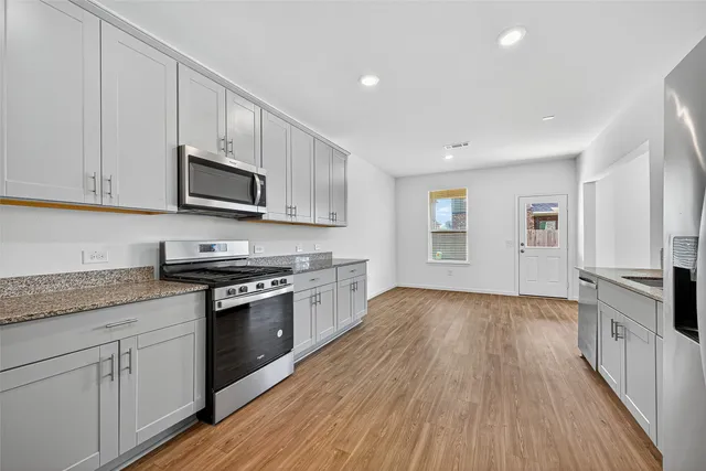 a kitchen with granite countertop wooden floors and stainless steel appliances