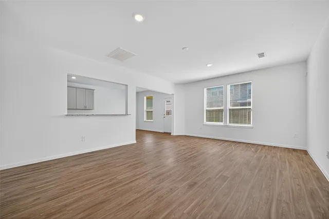 a view of empty room with wooden floor and windows