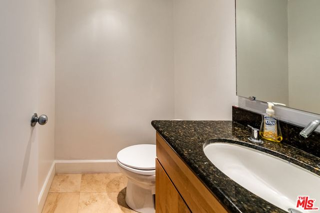 a bathroom with a granite countertop sink a toilet and a mirror