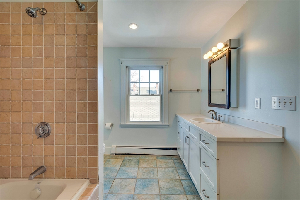 32 Emerson Road Needham, MA 02492 - Photo 19 of 27 a bathroom with a double vanity sink a mirror and a bathtub