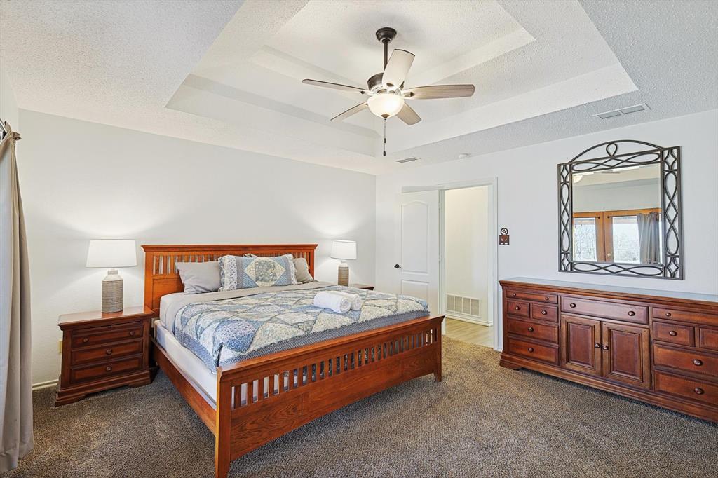 7185 Mesquite Ridge Sanger, TX 76266 - Photo 18 of 40 Bedroom with dark carpet, a tray ceiling, a textured ceiling, and ceiling fan