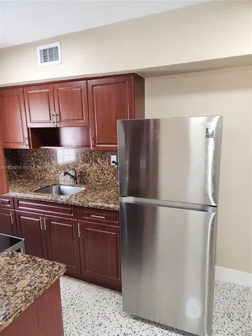 a kitchen with stainless steel appliances granite countertop a refrigerator and a sink