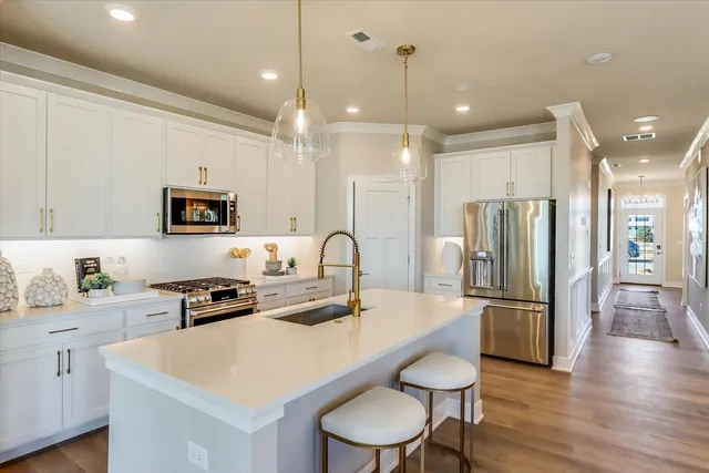 a kitchen with stainless steel appliances granite countertop a sink a stove a refrigerator and island with wooden floor