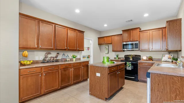 a kitchen with stainless steel appliances granite countertop wooden cabinets a stove top oven a sink and dishwasher with wooden floor