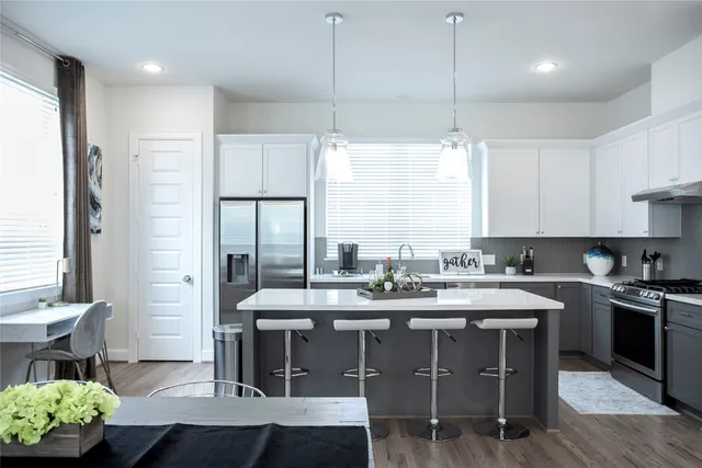 a kitchen with a stove a sink and a dining table with wooden floor