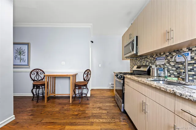 a kitchen with stainless steel appliances granite countertop a stove top oven a sink a dining table and chairs with wooden floor