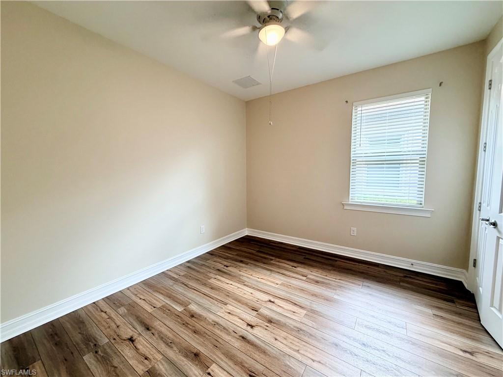 16432 Aberdeen Way Naples, FL 34110 - Photo 15 of 21 an empty room with wooden floor and windows