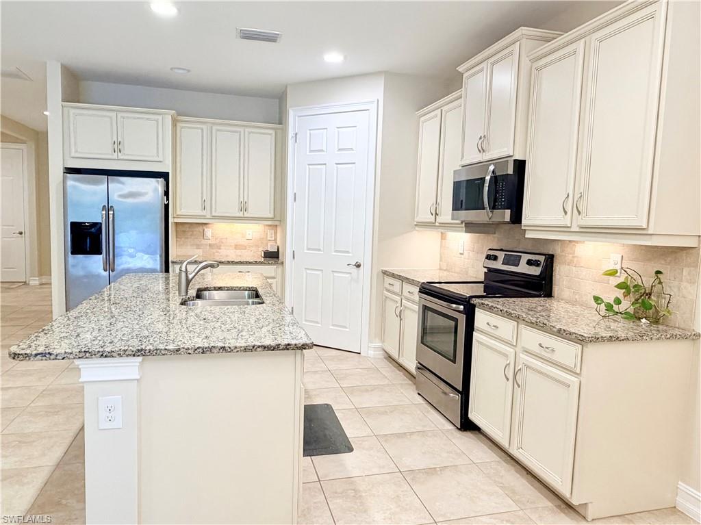 16432 Aberdeen Way Naples, FL 34110 - Photo 2 of 21 a kitchen with granite countertop a sink stainless steel appliances and white cabinets