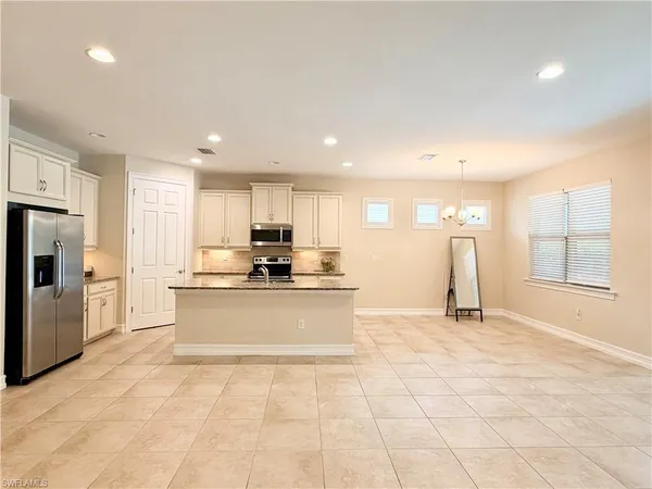 a large white kitchen with kitchen island a sink a counter and a large window