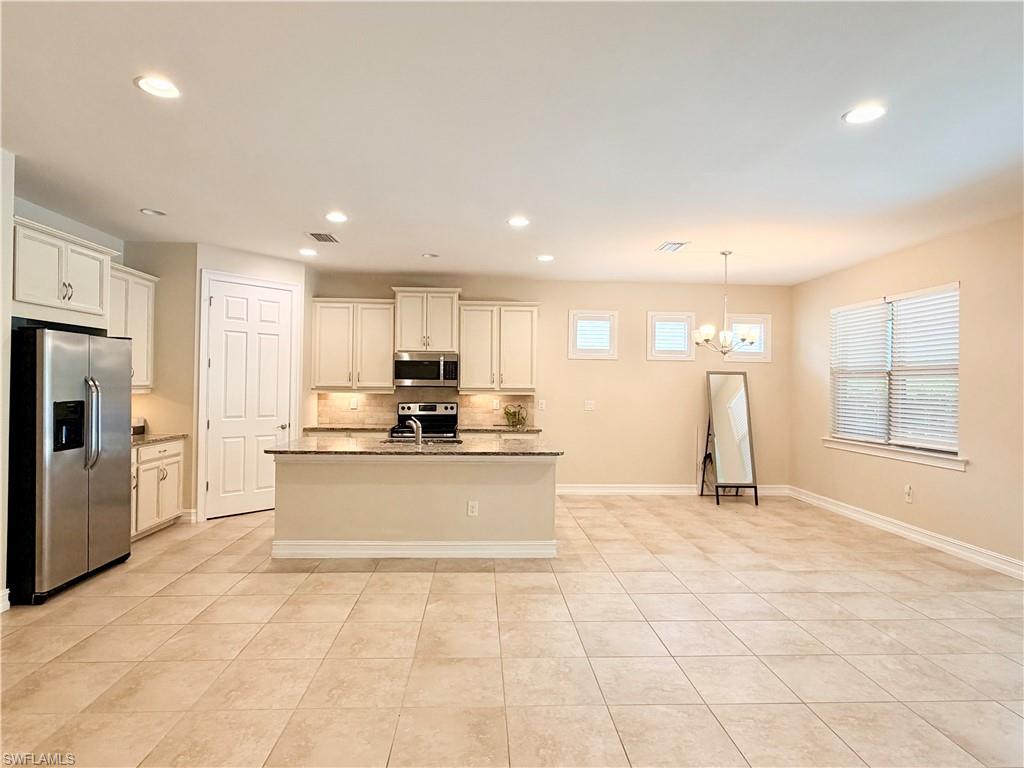 16432 Aberdeen Way Naples, FL 34110 - Photo 5 of 21 a large white kitchen with kitchen island a sink a counter and a large window