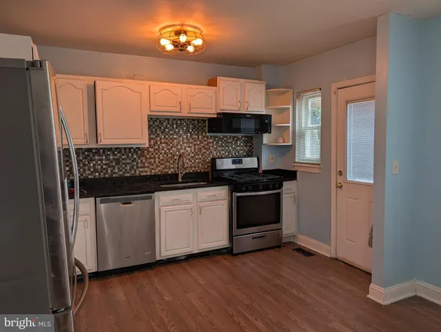 a kitchen with stainless steel appliances a sink cabinets and wooden floor