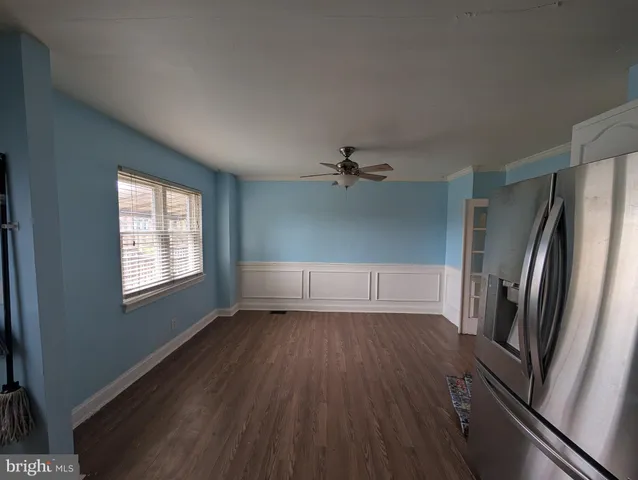 a view of a livingroom with wooden floor a ceiling fan and window