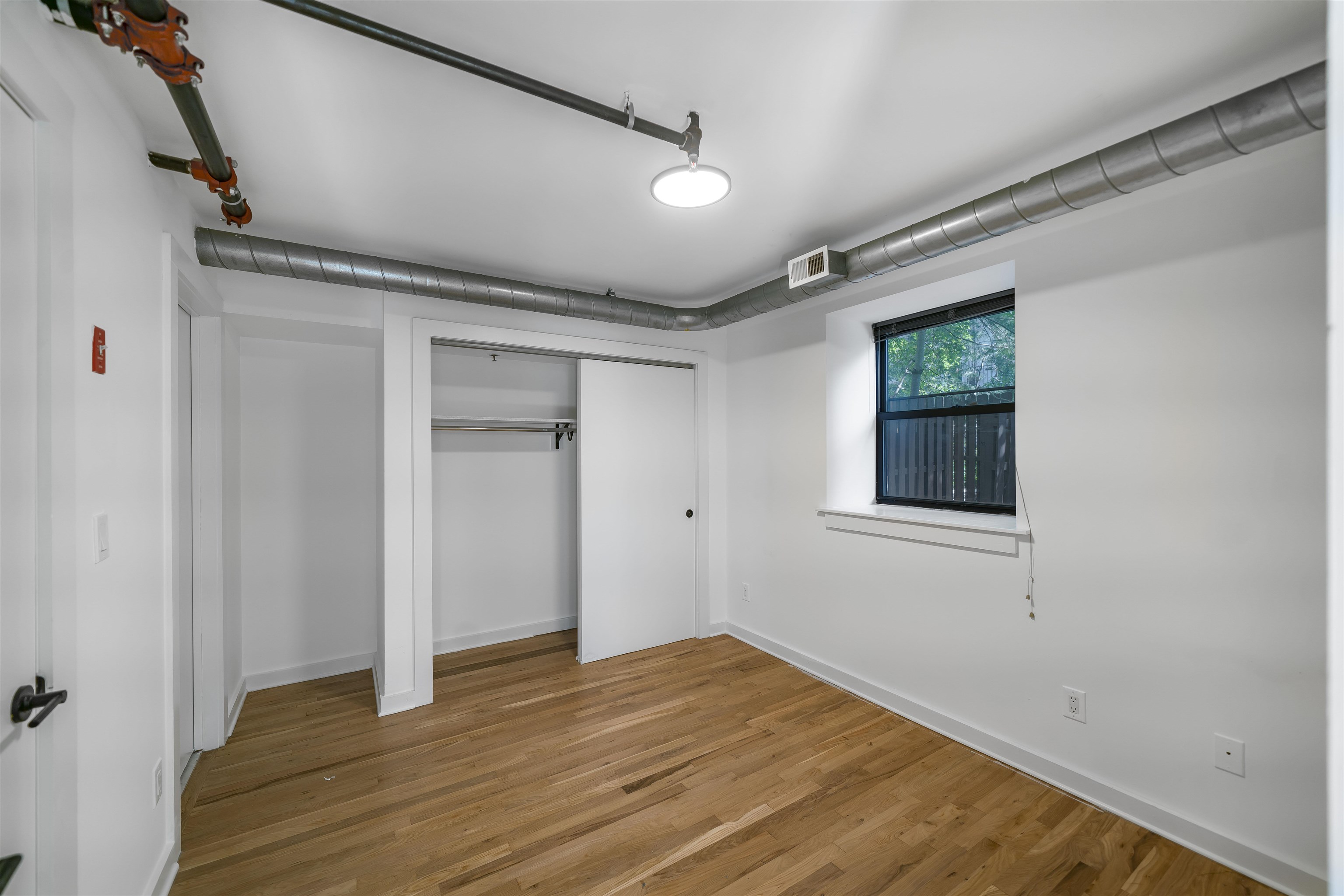 1015 Clinton Street, Unit 204 Hoboken, NJ 07030 - Photo 17 of 22 a view of an empty room with wooden floor and a window