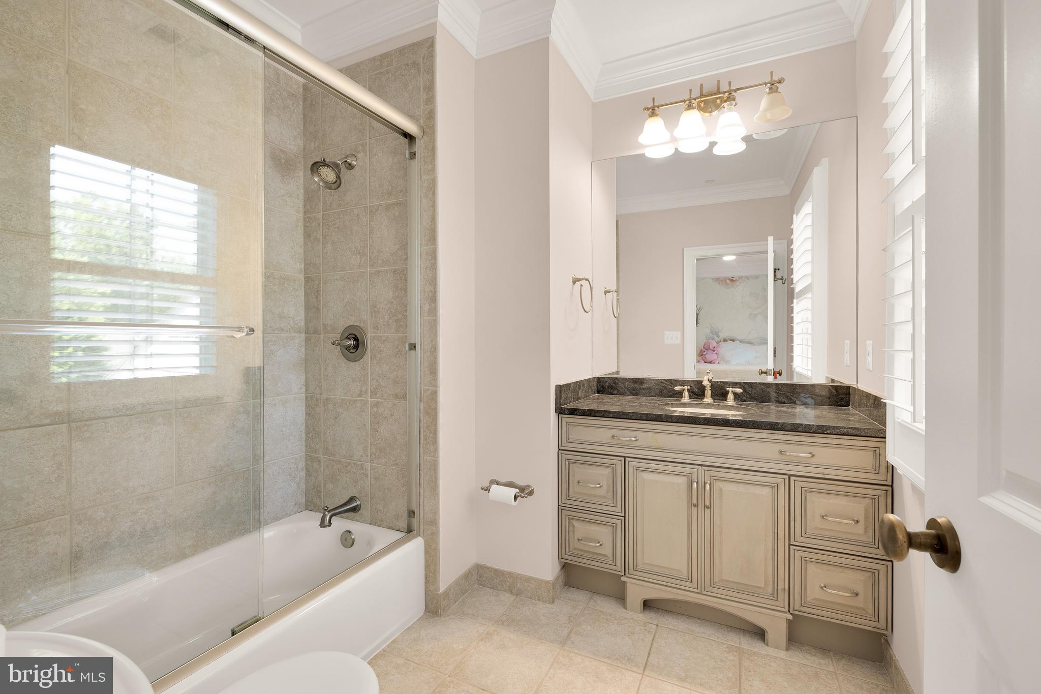 5606 Parkston Road Bethesda, MD 20816 - Photo 38 of 50 a bathroom with a granite countertop sink a mirror a bathtub and shower