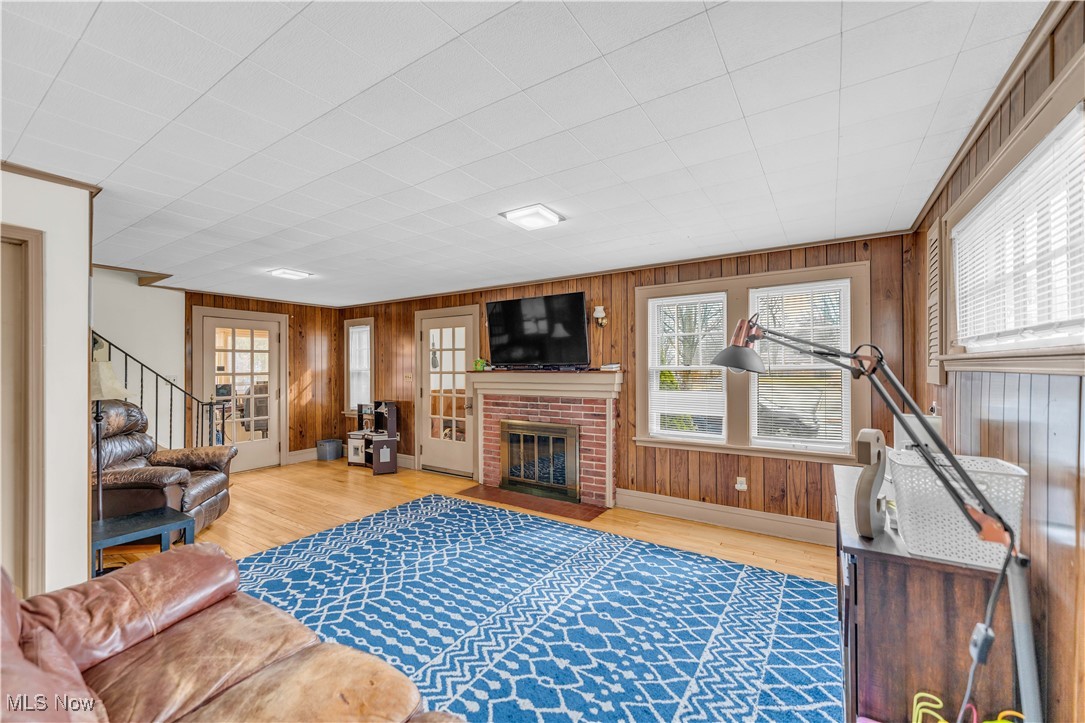 3729 Grosvenor Road Cleveland, OH 44118 - Photo 11 of 39 Living area with wooden walls, a fireplace, stairs, and wood finished floors