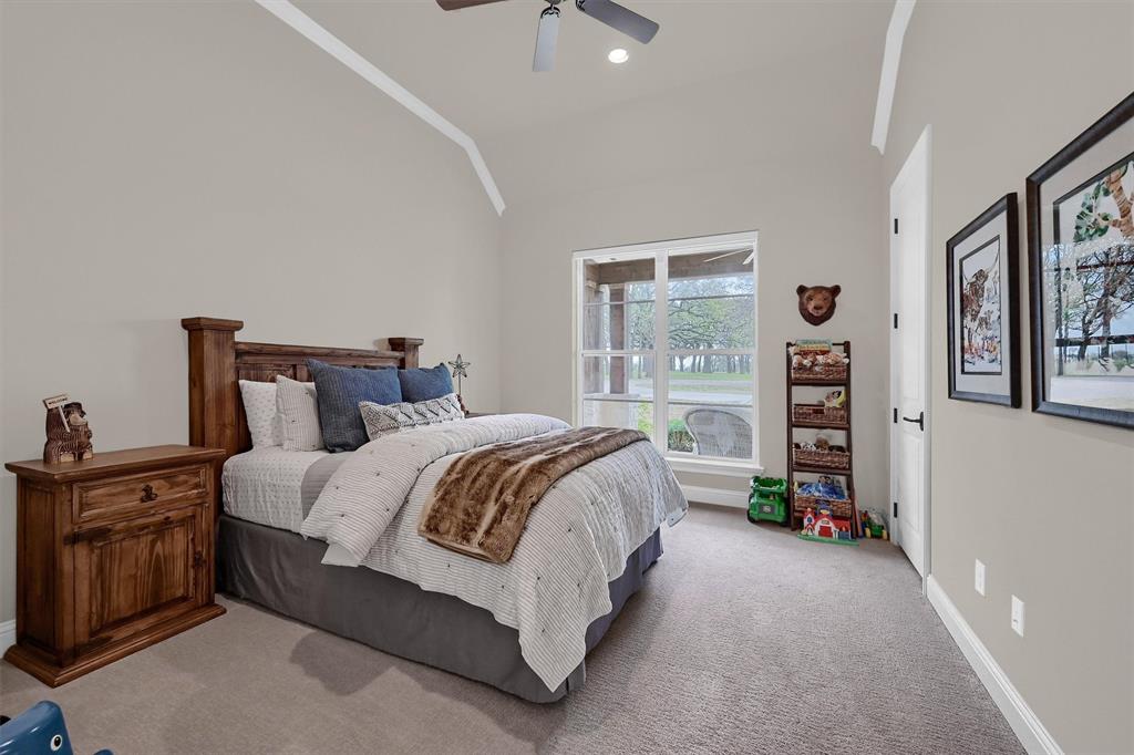 8301 Stephens Ranch Road Pilot Point, TX 76258 - Photo 28 of 40 a bedroom with a bed a dresser and a chandelier