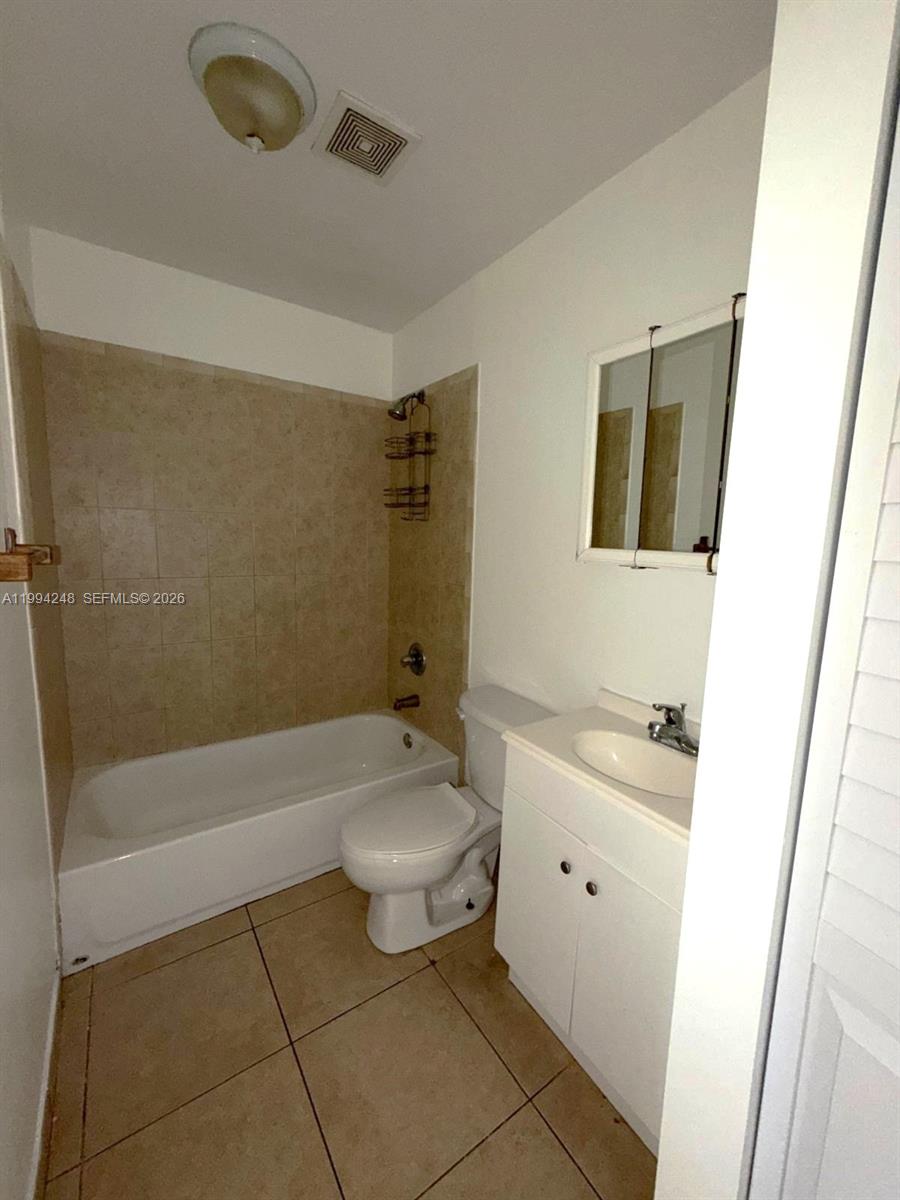 14140 Northeast 2nd Court, Unit 2 Miami, FL 33161 - Photo 5 of 13 a bathroom with a granite countertop sink a toilet and bathtub