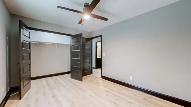 an empty room with closet and ceiling fan