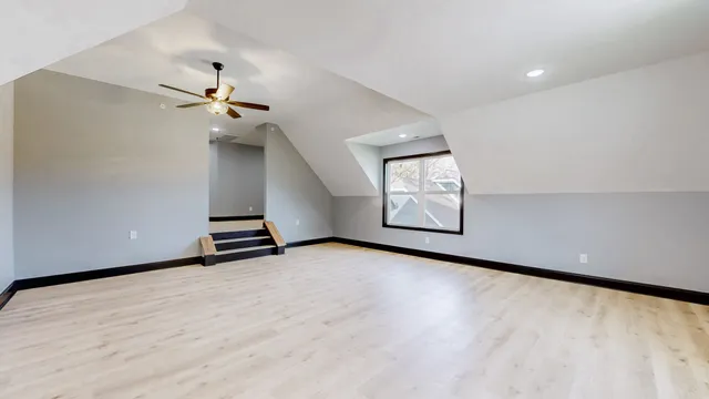 an empty room with windows and ceiling fan