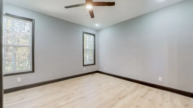 an empty room with windows and ceiling fan