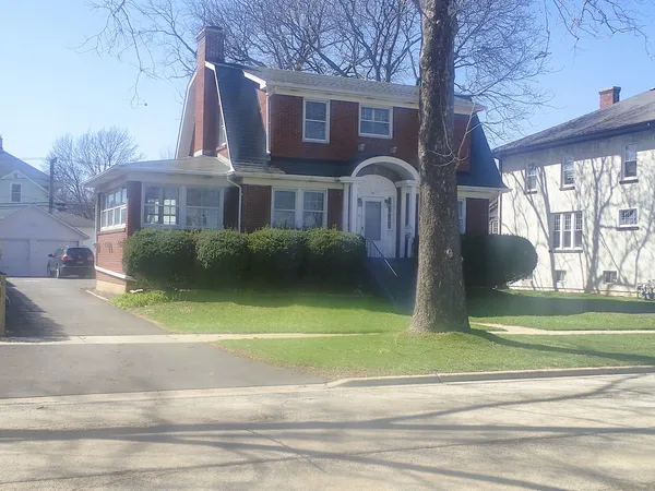 a front view of a house with a garden and trees