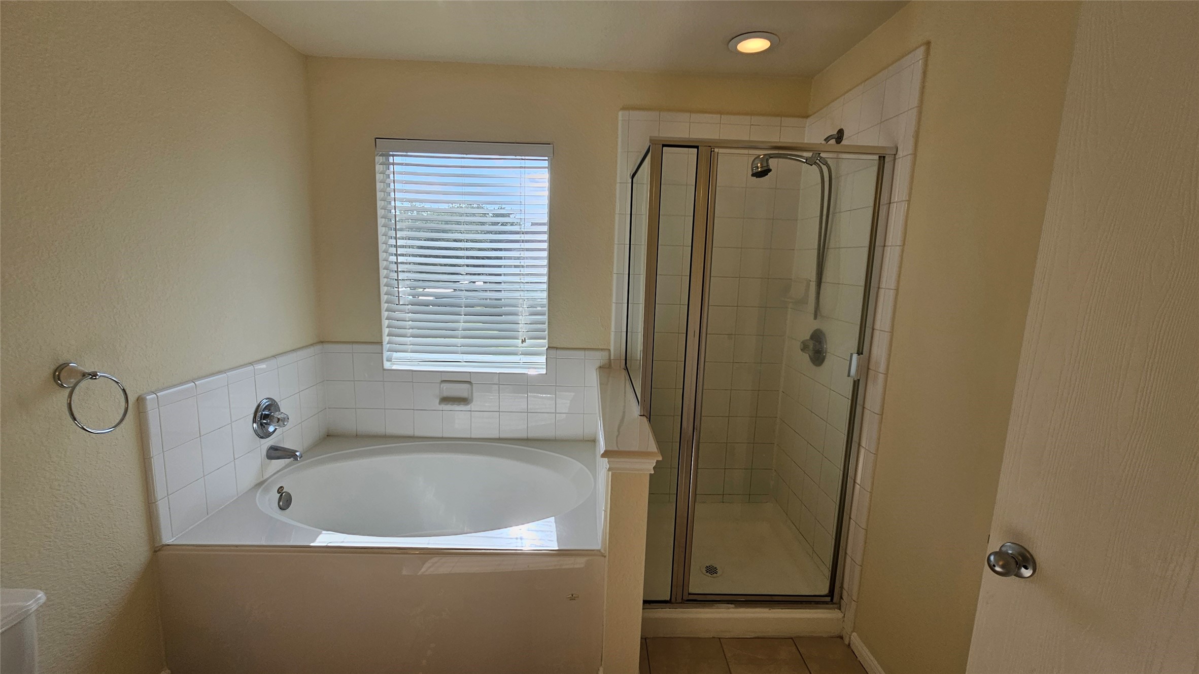 7918 Barnes Ridge Lane Houston, TX 77072 - Photo 24 of 34 This bathroom features a spacious corner bathtub and a separate glass-enclosed shower, with neutral-colored walls and tiled accents. Natural light filters through a window with blinds, creating a bright and inviting space.