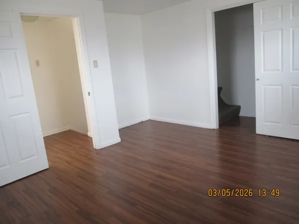 an empty room with wooden floor and entrance