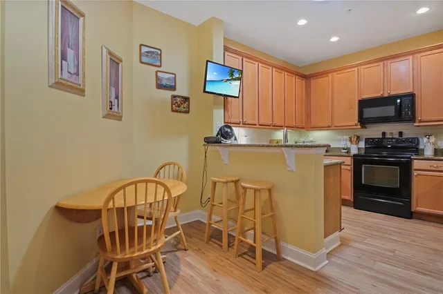 a kitchen with stainless steel appliances granite countertop a stove top oven a sink a dining table and chairs with wooden floor